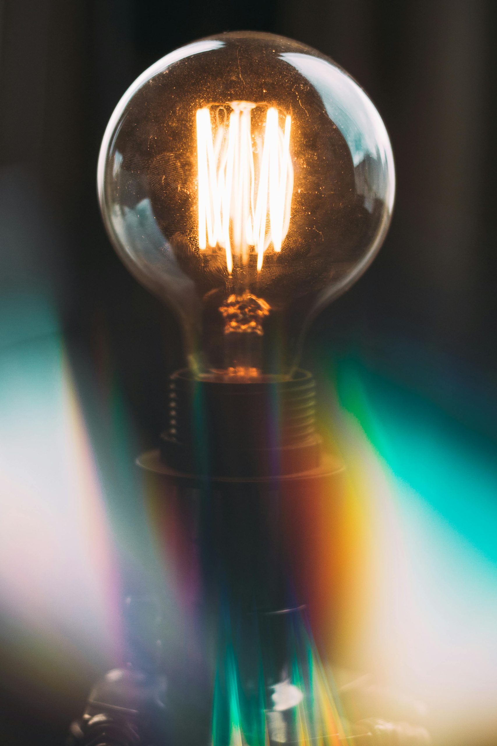 A beautifully illuminated Edison bulb glowing with rainbow reflections in a dark setting.